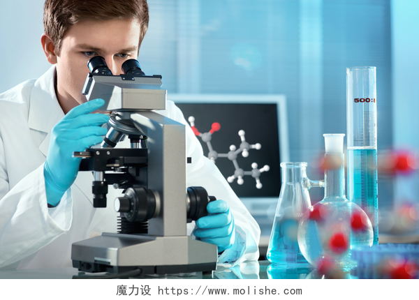 一个年轻的男人穿着白大褂在使用显微镜在实验室工作的科学家